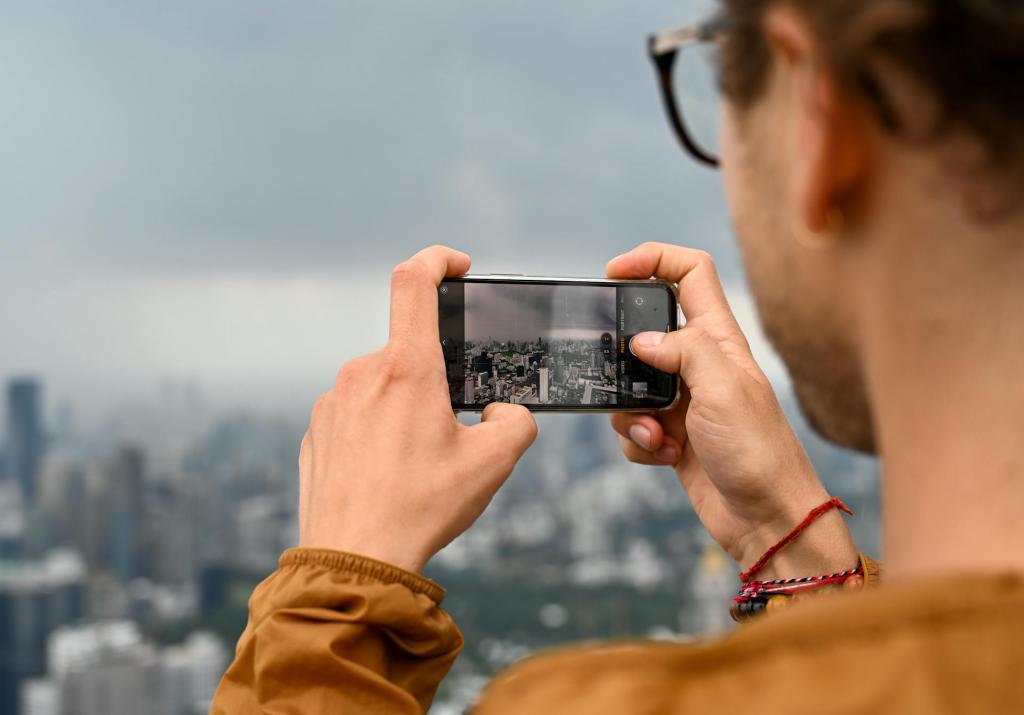 Mann mit sandfarbener Jacke hält ein Smartphone mit seinen Händen und fotografiert damit eine thailändische Stadt.