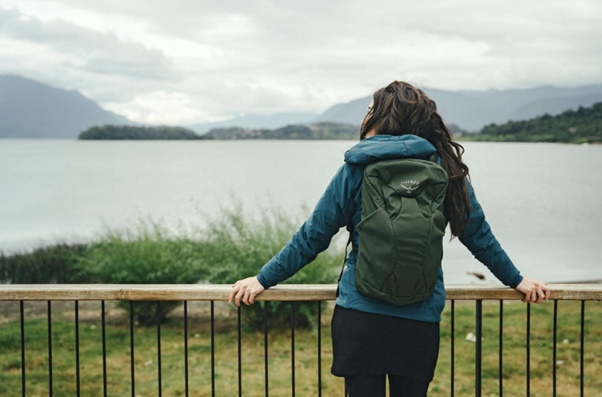 Eine Frau mit einem Rucksack, die vor einem großen See steht.